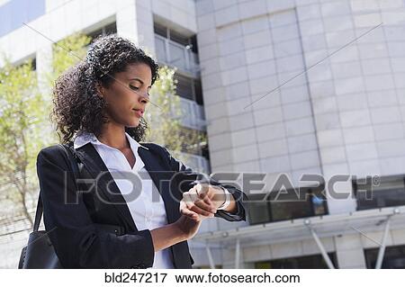 Mixed Race businesswoman checking wristwatch outdoors View Large Photo Image Stock Photo - Mixed Race businesswoman checking wristwatch outdoors. Fotosearch