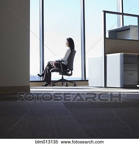 Stock Photography - Mixed race businesswoman looking out office window. Fotosearch