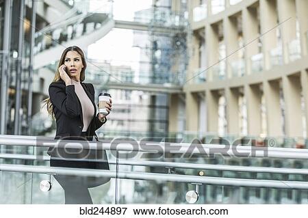 Mixed Race businesswoman talking on cell phone in lobby View Large Photo Image Stock Photo - Mixed Race businesswoman talking on cell phone in lobby. Fotosearch