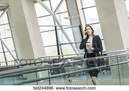 Mixed Race businesswoman talking on cell phone in lobby View Large Photo Image Stock Photograph - Mixed Race businesswoman talking on cell phone in lobby. Fotosearch