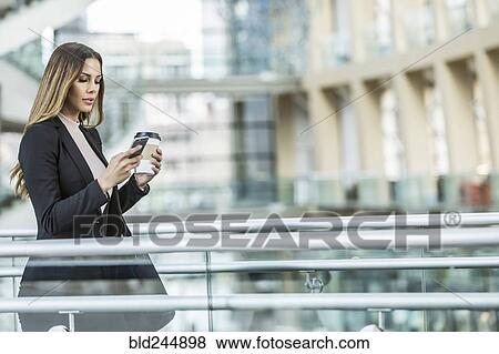 Stock Photo - Mixed Race businesswoman texting on cell phone in lobby. Fotosearch