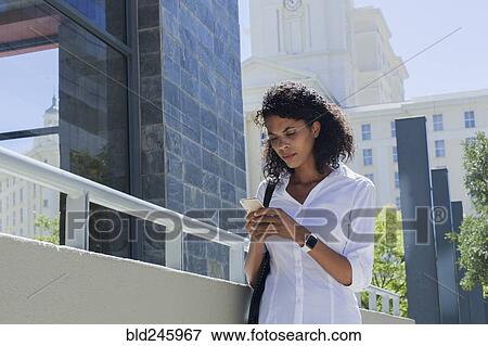 Mixed Race businesswoman texting on cell phone outdoors View Large Photo Image Stock Photo - Mixed Race businesswoman texting on cell phone outdoors. Fotosearch