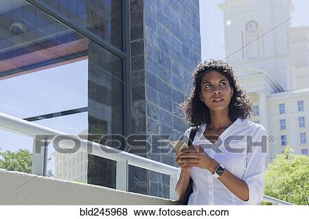 Mixed Race businesswoman texting on cell phone outdoors View Large Photo Image Stock Photo - Mixed Race businesswoman texting on cell phone outdoors. Fotosearch