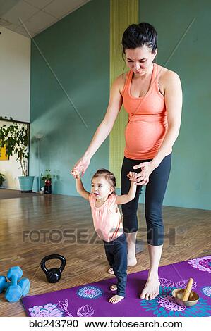 Mixed Race expectant mother holding hands of daughter on exercise mat View Large Photo Image Stock Image - Mixed Race expectant mother holding hands of daughter on exercise mat. Fotosearch