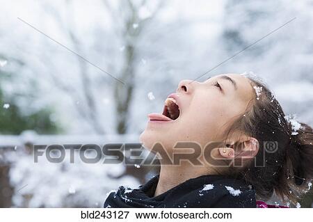 Stock Photo - Mixed Race girl catching snowflakes on tongue. Fotosearch