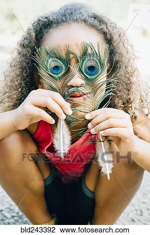 Mixed Race girl covering eyes with peacock feathers View Large Photo Image Stock Image - Mixed Race girl covering eyes with peacock feathers. Fotosearch