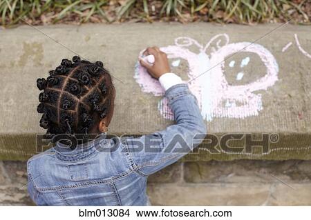 Picture - Mixed race girl drawing on cement with chalk. Fotosearch