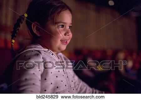 Stock Photo - Mixed Race girl watching movie in theater. Fotosearch