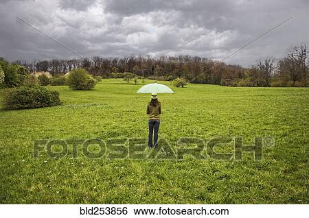 Mixed Race holding umbrella in field View Large Photo Image Stock Photograph - Mixed Race holding umbrella in field. Fotosearch