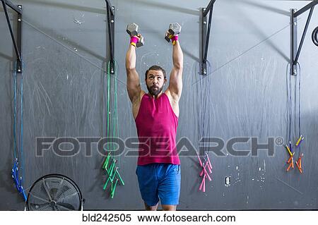 Stock Photography - Mixed Race man lifting dumbbells in gymnasium. Fotosearch