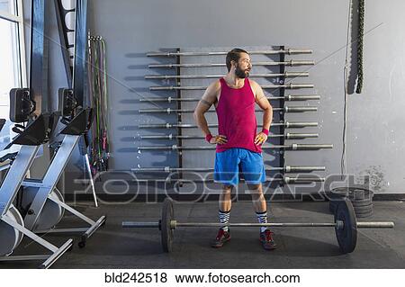 Mixed Race man resting near barbell in gymnasium View Large Photo Image Stock Photo - Mixed Race man resting near barbell in gymnasium. Fotosearch
