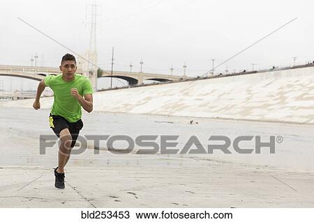 Stock Image - Mixed Race man running in canal. Fotosearch