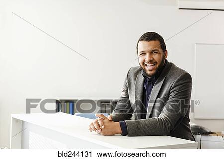 Stock Image - Mixed Race man smiling in office. Fotosearch