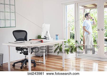 Stock Image - Mixed Race man talking on cell phone on patio. Fotosearch
