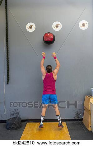 Mixed Race man throwing heavy ball against wall View Large Photo Image Stock Image - Mixed Race man throwing heavy ball against wall. Fotosearch