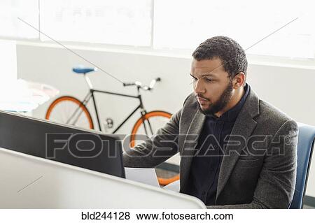Stock Photo - Mixed Race man using computer in office. Fotosearch