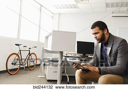 Mixed Race man using digital tablet in office View Large Photo Image Stock Image - Mixed Race man using digital tablet in office. Fotosearch