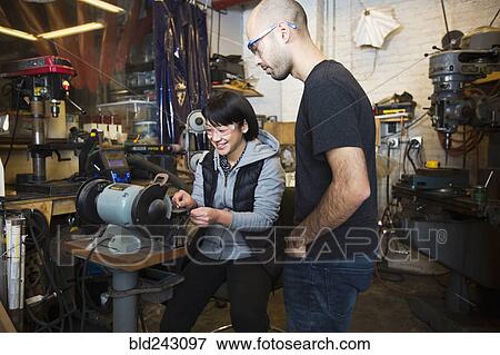 Stock Photo - Mixed Race man using machinery in workshop. Fotosearch