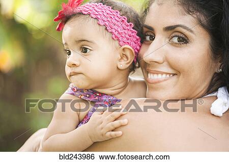 Stock Photograph - Mixed Race mother holding baby daughter. Fotosearch