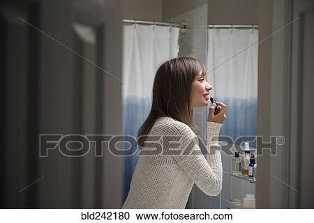 Mixed Race woman applying lipstick in bathroom View Large Photo Image Stock Image - Mixed Race woman applying lipstick in bathroom. Fotosearch