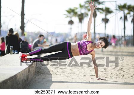 Stock Image - Mixed Race woman balancing on arm at beach. Fotosearch