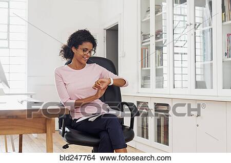 Picture - Mixed Race woman checking wristwatch. Fotosearch