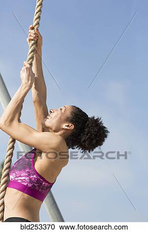 Mixed Race woman climbing rope outdoors View Large Photo Image Stock Image - Mixed Race woman climbing rope outdoors. Fotosearch