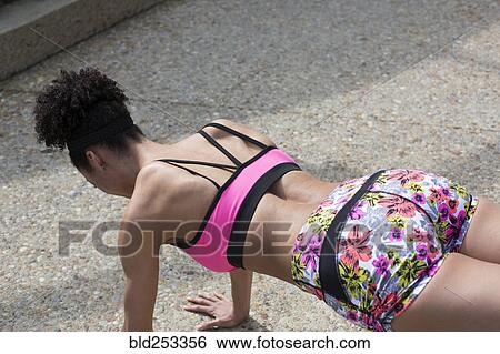 Stock Photograph - Mixed Race woman doing push-ups on path. Fotosearch