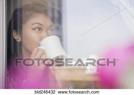 Mixed Race woman drinking coffee behind window View Large Photo Image Stock Image - Mixed Race woman drinking coffee behind window. Fotosearch