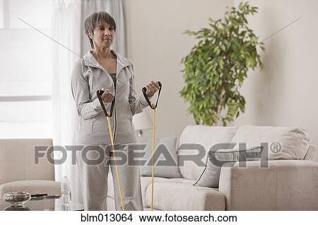 Picture - Mixed race woman exercising in living room. Fotosearch