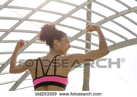 Stock Photo - Mixed Race woman flexing arms. Fotosearch