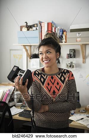 Stock Photo - Mixed Race woman holding camera. Fotosearch