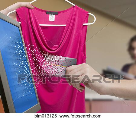 Stock Photography - Mixed race woman holding pixilated credit card near computer. Fotosearch
