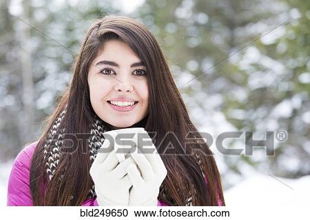 Stock Image - Mixed Race woman holding warm beverage outdoors in winter. Fotosearch