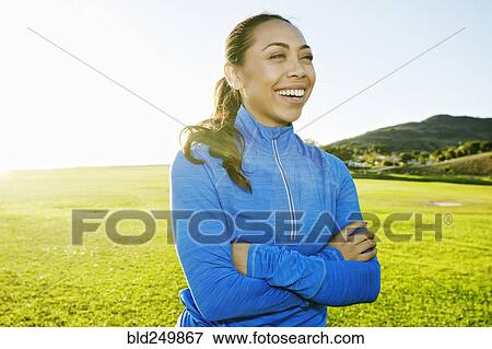 Stock Photo - Mixed Race woman laughing in sunny field. Fotosearch