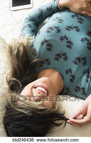Mixed Race woman laying on bed pulling hair over eyes View Large Photo Image Stock Photo - Mixed Race woman laying on bed pulling hair over eyes. Fotosearch