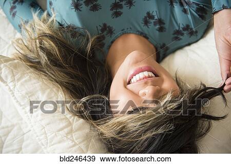 Mixed Race woman laying on bed pulling hair over eyes View Large Photo Image Stock Photo - Mixed Race woman laying on bed pulling hair over eyes. Fotosearch