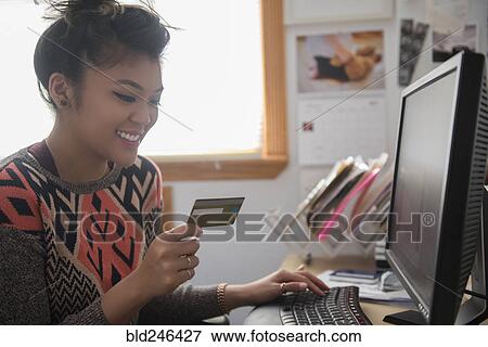 Stock Photo - Mixed Race woman online shopping using computer. Fotosearch
