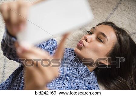 Stock Photo - Mixed Race woman posing for cell phone selfie. Fotosearch