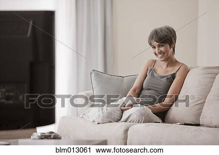 Stock Image - Mixed race woman relaxing on sofa. Fotosearch