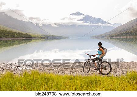 Mixed Race woman riding a bicycle near lake View Large Photo Image Stock Photo - Mixed Race woman riding a bicycle near lake. Fotosearch