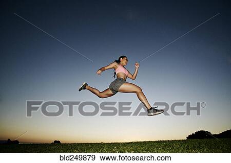 Mixed Race woman running and jumping in field at sunset View Large Photo Image Stock Photo - Mixed Race woman running and jumping in field at sunset. Fotosearch