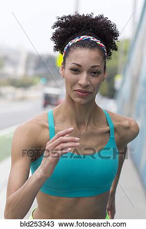 Stock Image - Mixed Race woman running on sidewalk. Fotosearch