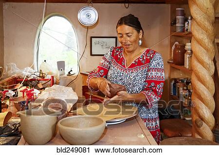 Stock Image - Mixed race woman shaping clay in art studio. Fotosearch
