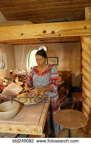 Stock Image - Mixed race woman shaping clay in art studio. Fotosearch