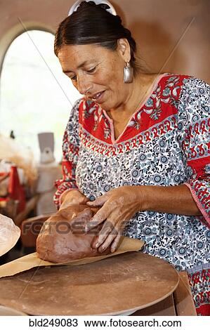 Stock Image - Mixed race woman shaping clay in art studio. Fotosearch
