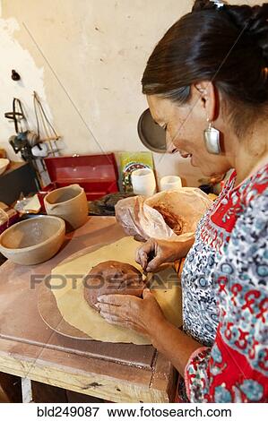 Stock Photo - Mixed race woman shaping clay mask in art studio. Fotosearch