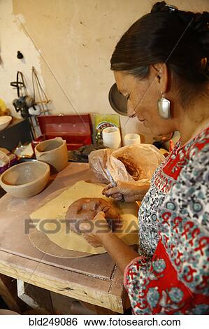 Stock Photograph - Mixed race woman shaping clay mask in art studio. Fotosearch