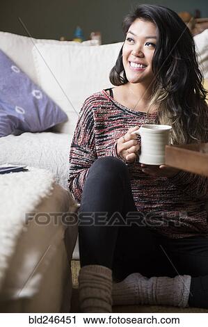 Mixed Race woman sitting on floor drinking coffee View Large Photo Image Stock Image - Mixed Race woman sitting on floor drinking coffee. Fotosearch