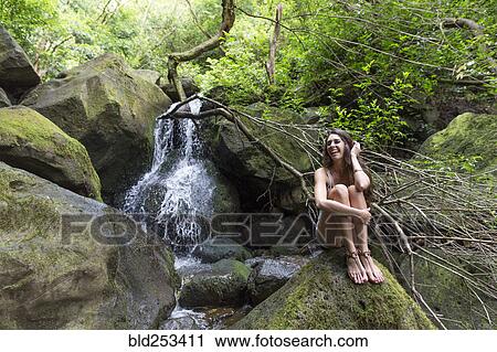 Mixed Race woman sitting on rock near waterfall View Large Photo Image Stock Image - Mixed Race woman sitting on rock near waterfall. Fotosearch